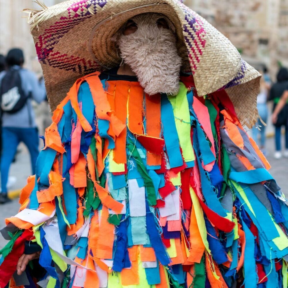Colorful traditional costume at Oaxaca street festival captured in lively city scene.